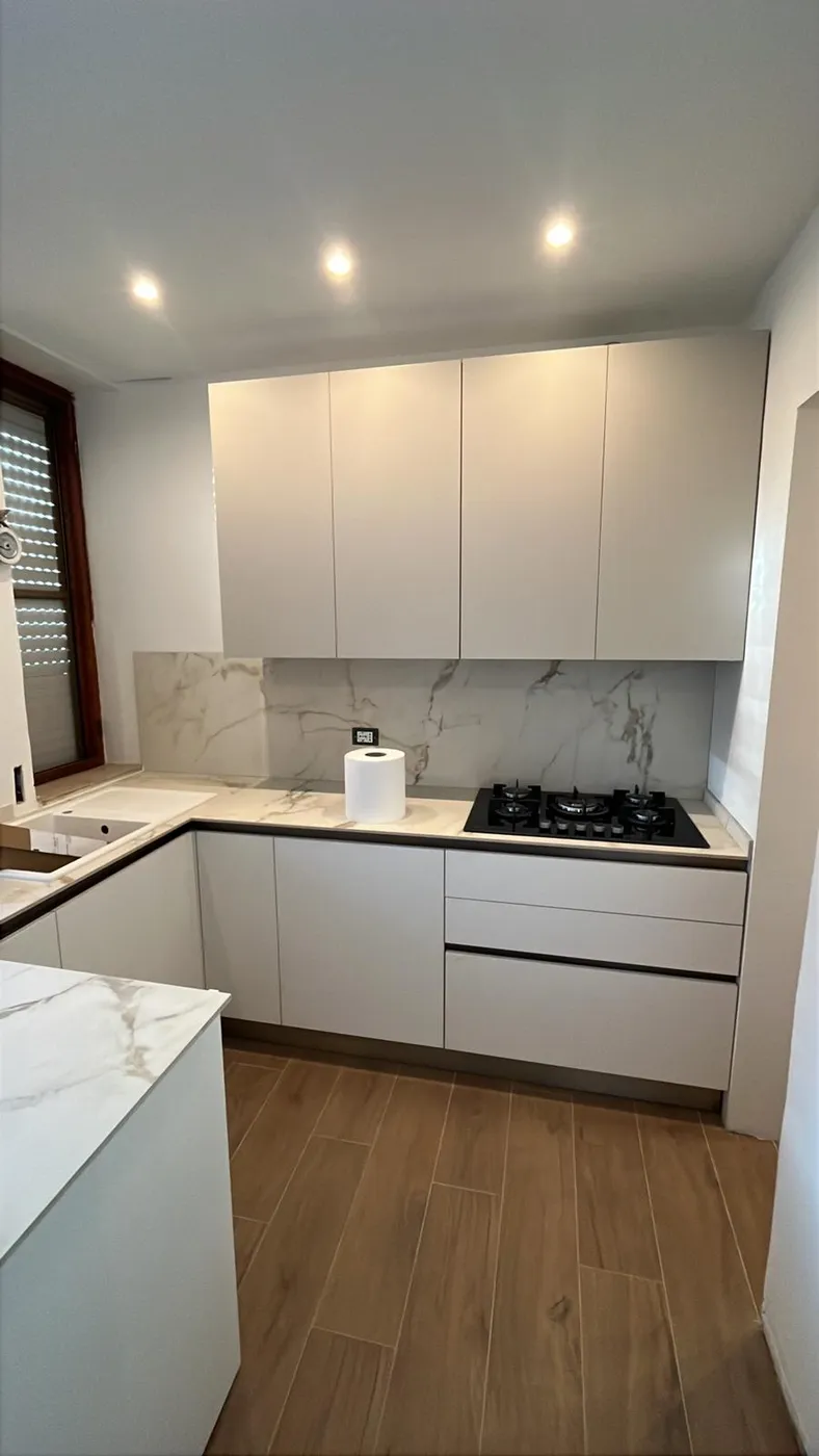 Cucina bianca con pensili fino a soffitto e schienale in marmo Calacatta