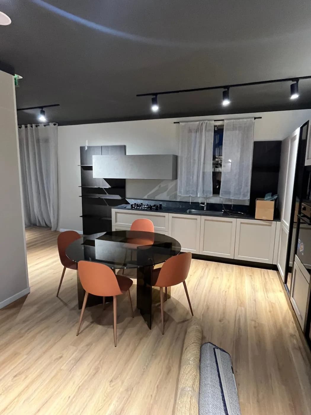 Cucina in stile classico bianca con vetrine nere e tavolo rotondo in vetro