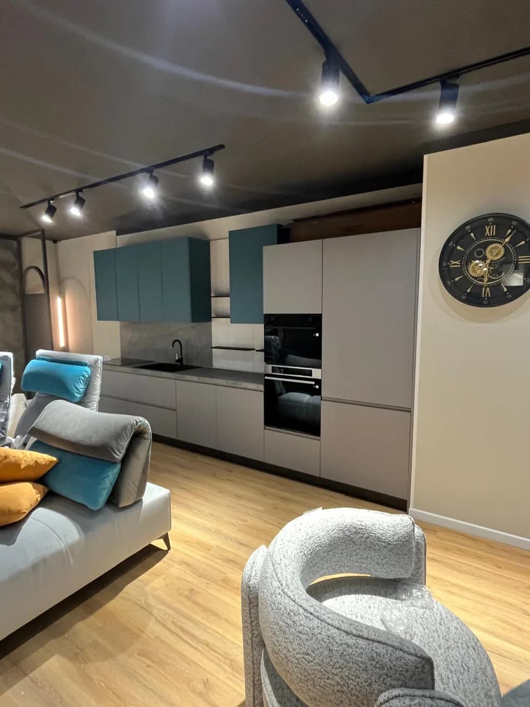 Cucina grigia con pensili verde petrolio, colonne forno e zona living