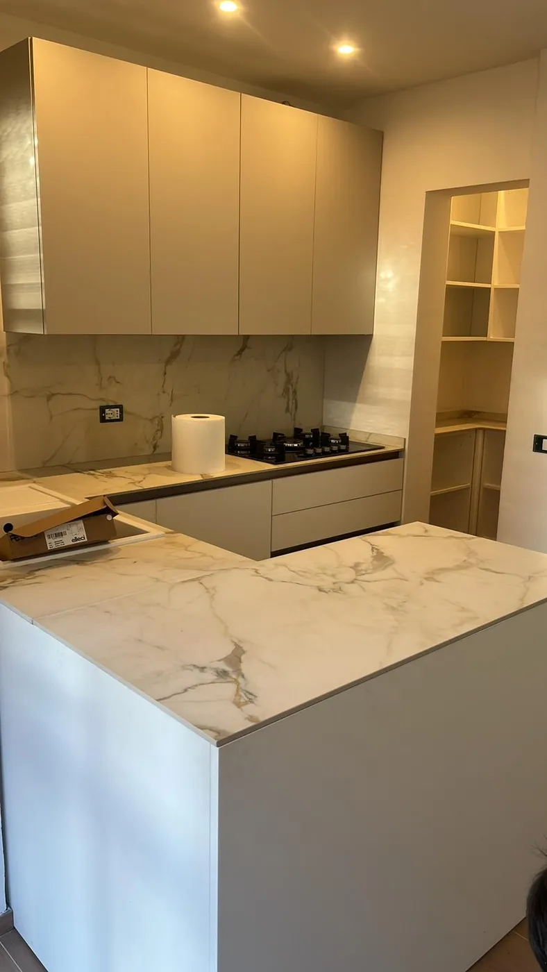 Isola cucina con piano in marmo, piano cottura a gas e dispensa a giorno