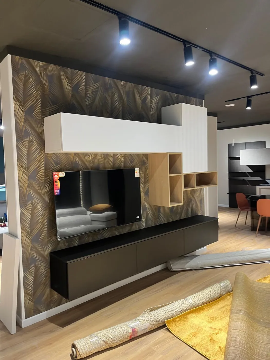 Parete TV con mobili sospesi bianchi, vani a giorno e carta da parati decorativa