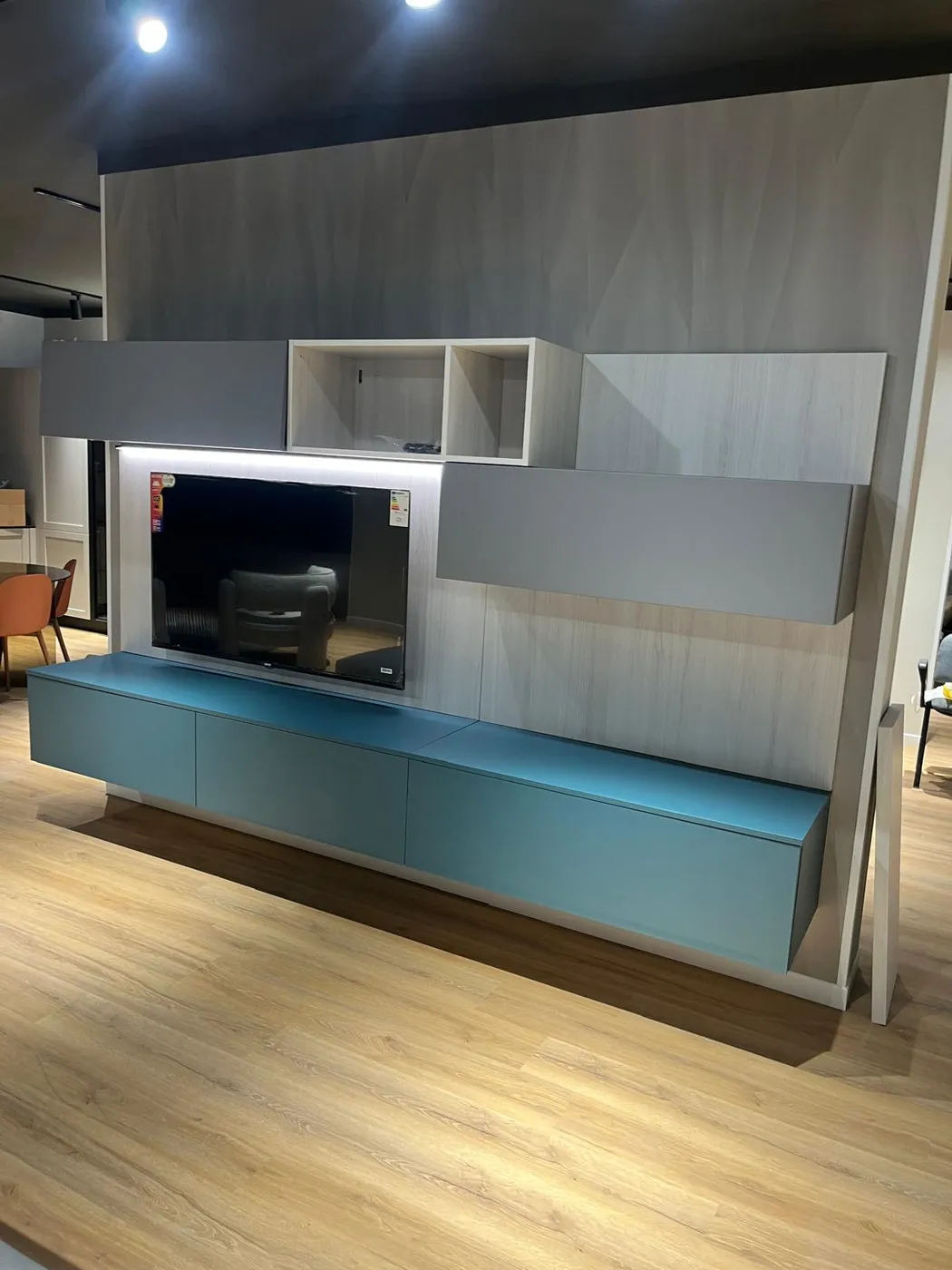 Parete attrezzata TV con mobile sospeso azzurro e pensili grigi